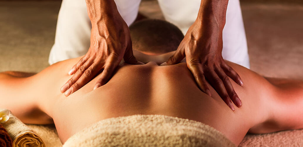 Professional massage therapist providing back massage to client on table